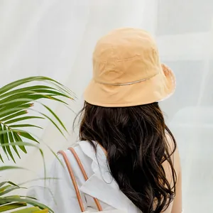 Detail view of the orange cotton bucket hat with plaid inner lining and smooth round top