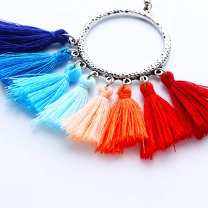 Detalle de pendientes bohemios con aro de plata martillada y borlas de seda de colores vivos