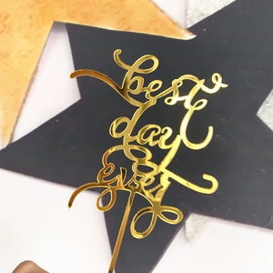 Close-up of golden acrylic best day ever cake topper with reflective mirror finish