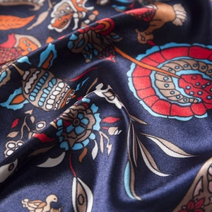 Macro shot of 90cm silk scarf showing smooth navy fabric with colorful floral pattern