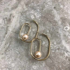 Minimalist gold plated oval frame drop earrings with elegant pearl pendant on grey surface