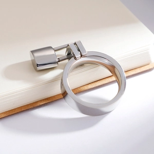 Polished silver 6mm ring with rectangular padlock pendant leaning on notebook edge