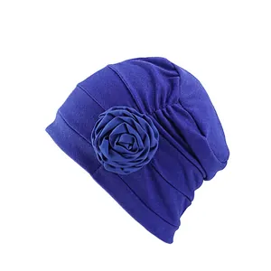 Détail du turban bleu marine avec une grande rose en tissu et une texture plissée élégante