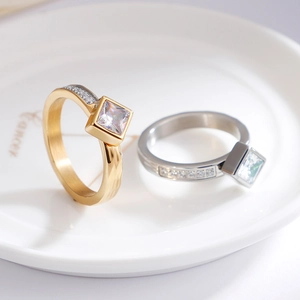 Square cubic zirconia stainless steel rings in gold and silver finish on white ceramic