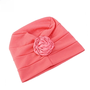 Gros plan d'un bonnet turban rouge pastèque avec élégante fleur de rose en satin