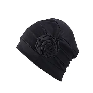 Détail d'un turban noir élégant avec plis et grand ornement de fleur latérale