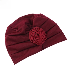 Détail du turban bordeaux avec grande fleur de rose et texture plissée douce