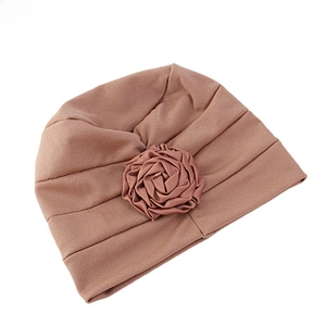 Détail d'un turban rose poudré avec une rose en satin faite main et une texture côtelée