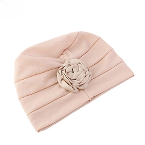 Détail d'un turban rose avec une fleur rose faite à la main et un design plissé élégant