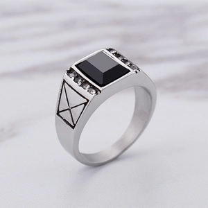 Bague pour homme en acier argenté avec pierre noire carrée et cristaux sur marbre
