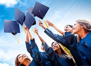 Graduates throwing navy blue graduation caps into the sky for celebration