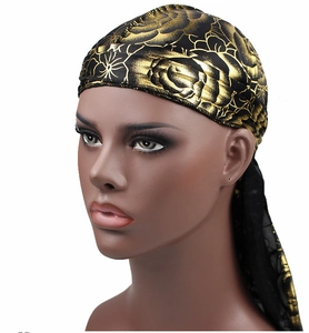 Close-up of silky durag featuring golden rose floral patterns on black fabric