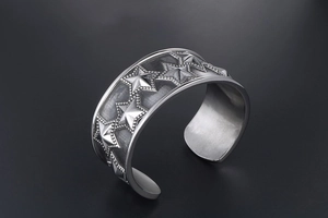 Detail of vintage silver titanium steel open cuff bracelet with embossed stars and beads