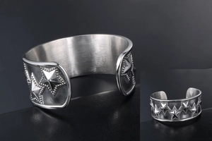 Detail view of punk style stainless steel cuff bracelet with embossed star patterns