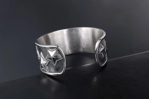 Detailed macro shot of vintage star relief and grain texture on stainless steel cuff