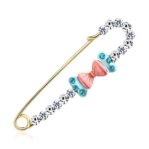 Macro detail of golden bow brooch with sparkling rhinestones and pink blue enamel