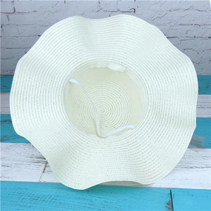 Creamy white wide brim straw hat with wavy edges and adjustable wind strap for sun protection