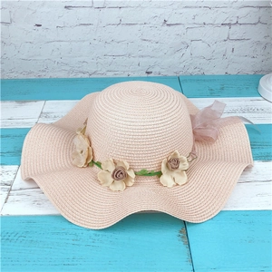 Chapeau de paille rose avec couronne de fleurs et large bord ondulé pour les vacances