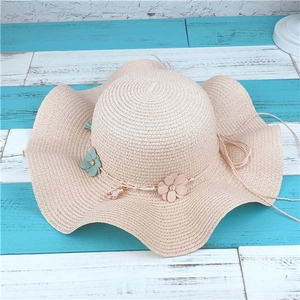 Chapeau de soleil en paille rose à bord ondulé avec fleurs pour vacances à la plage