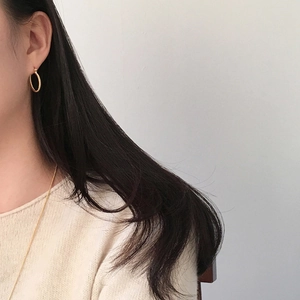 Close-up of golden twisted rope hoop earrings worn on ear with vintage woven texture