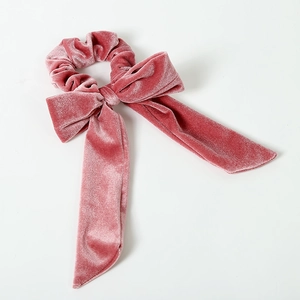 Detailed macro view of pink velvet bow scrunchie showing soft texture and glossy finish