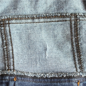 Close-up of vintage blue denim dog vest showing durable fabric texture and double stitching