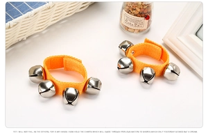 Close-up of bright orange wrist bells with silver metal bells and adjustable velcro strap