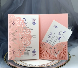 Detail of pink laser-cut wedding invitation with lace pattern on elegant tray