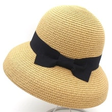 Detailed view of women's straw hat featuring a fine herbal weave and black ribbon bow