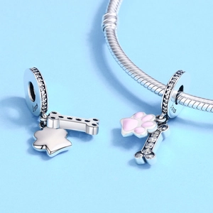 Detailed view of S925 sterling silver dog bone and pink enamel paw charms on a bracelet
