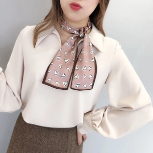 Close-up of pink heart pattern skinny scarf tied in a bow on a woman's neck