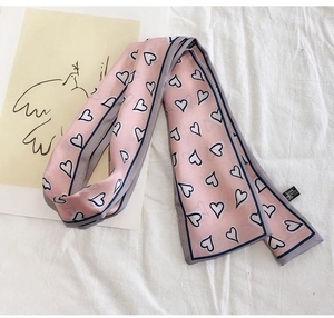 Close-up of pink heart print twilly silk scarf with navy trim on white fabric