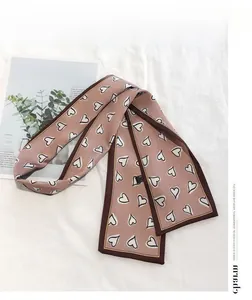 Detailed close-up of a pink silky skinny scarf featuring heart patterns and contrast borders