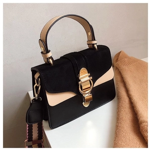Detail of contrast stitching, suede panel, and golden horseshoe buckle on stylish crossbody bag