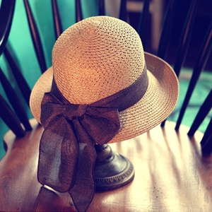 Vintage straw sun hat with wide brown ribbon bow on a display stand for women