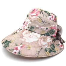 Detail of pink floral sun hat with large bow and golden embroidery on textured fabric