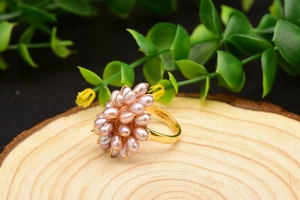 Gros plan de perles naturelles violettes en forme de fleur sur une bague dorée