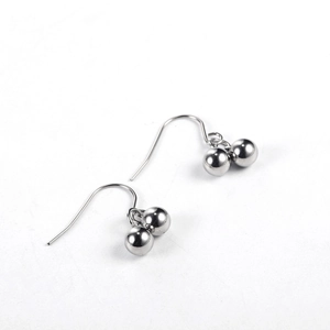 Macro detail of silver-finish steel hook earrings featuring double spherical bead drops