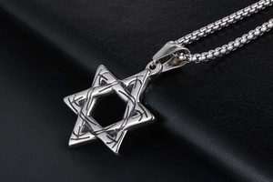 Close-up of vintage hollow hexagram pendant on silver snake chain over black leather