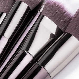 Macro shot of purple gradient makeup brushes with glossy black chrome ferrules and soft bristles