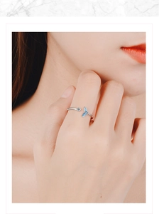 Detailed close-up of a silver fishtail ring with a blue tail and a sparkling diamond