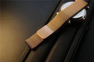 Detailed macro view of rose gold mesh watch strap with stainless steel case back