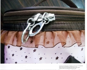 Detail of star print makeup bag with double metal zippers and brown ruffle trim details