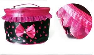 Macro detail of black satin makeup bag featuring pink hearts, lace trim and bow accent