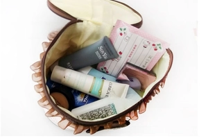 Top view of an open brown ruffled cosmetic bag filled with various skincare products