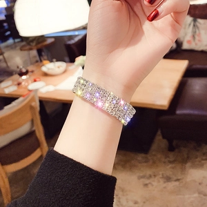 Macro shot of silver-tone multi-row rhinestone bracelet on wrist in warm indoor lighting