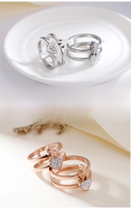 Detail of interlocking triple-band rings with heart and girl charms in silver and rose gold