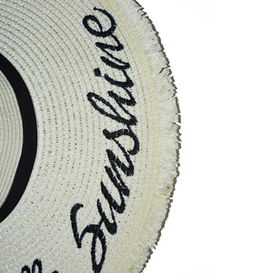 Detailed macro view of woven straw hat brim with fringe and Sunshine embroidery
