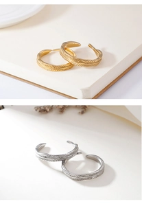 Detail of feather pattern earrings with gold and silver metallic brushed finish texture