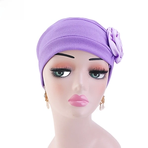 Détail d'un turban violet pour femme avec fleur latérale et texture en maille douce
